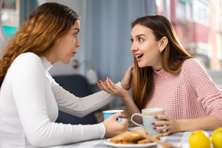 Two friends engaging in word-of-mouth marketing over coffee after completing a digital marketing diploma.