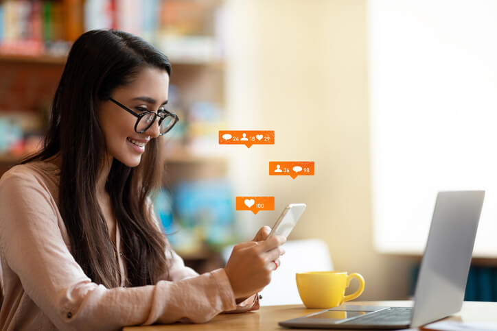A female digital marketing professional checking her social media engagement after completing her digital marketing diploma program.